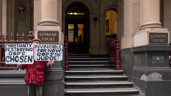 A protesters holding placards opposing the Catholic Church protests outside the Victorian Supreme court.