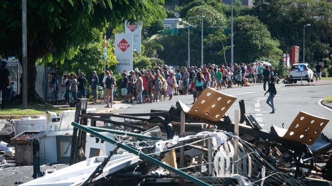 People wait in line to buy provisions from a supermarket along a street blocked by debris and burnt out items following overnight unrest in the Magenta district of Noumea, New Caledonia. Picture: Delphine Mayeur / AFP