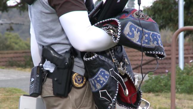 Law enforcement officer holds a rebel motorcycle club leather vest seized in raids on bikie clubhouses across Tasmania