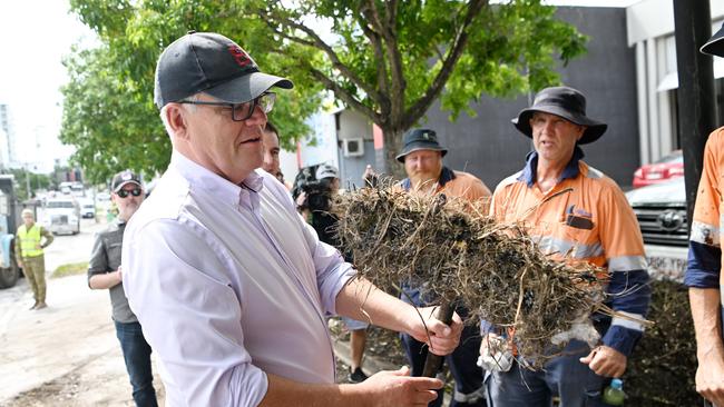 Prime Minister Scott Morrison looks at a well used broom as he meets workers at a flood-affected street in Milton, Brisbane. Picture: NCA NewsWire / Dan Peled