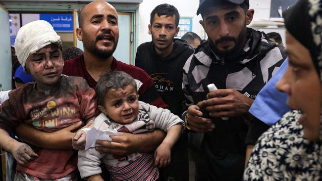 A man carries children injured in Israeli bombardment, at the al-Najjar hospital in Rafah in the southern Gaza Strip. Picture: AFP