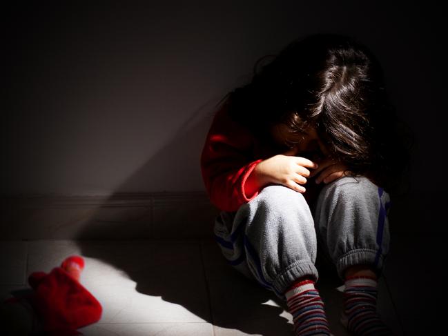 young girl sitting down alone in the dark.