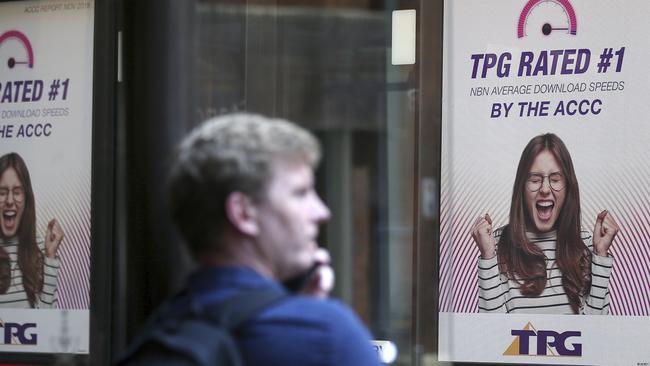 A bus branded with TPG ads passes a pedestrian. The telco has abandoned the rollout of what would have been Australia’s fourth mobile network due to the government’s ban on Huawei, which would have supplied equipment. Picture: AP