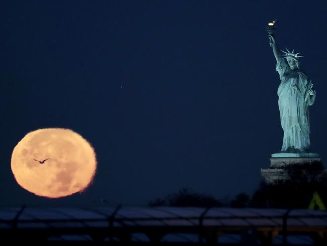 The supermoon appears near the Statue of Liberty, Monday, Nov. 14, 2016, in New York. Monday’s supermoon, a phenomenon that happens when the moon makes a close pass at the earth, is the closest to earth since 1948. Picture: AP Photo/Julio Cortez