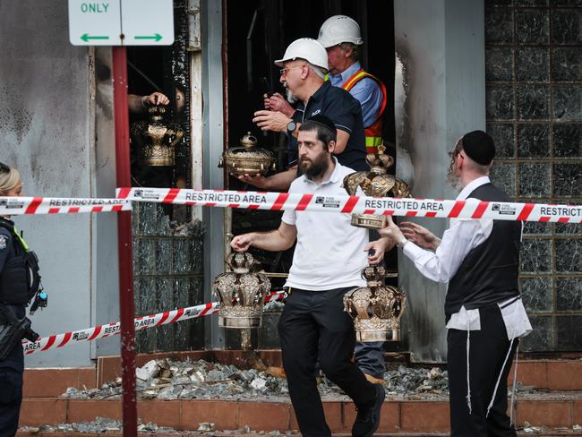 Members of the Jewish community remove religious artefacts from the burnt remains of their synagogue. Picture: David Caird