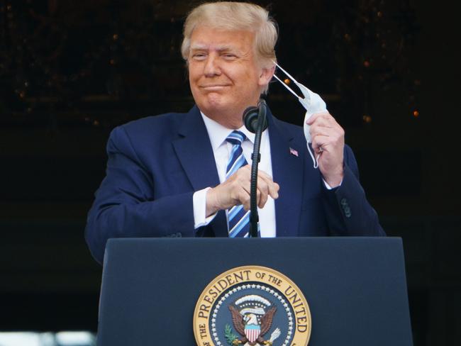 (FILES) In this file photo taken on October 10, 2020 US President Donald Trump takes his mask off before speaking from the South Portico of the White House in Washington, DC during a rally. - US President Donald Trump on October 11, 2020 declared himself immune from Covid-19 as he prepares to return to the election campaign trail and fight to regain ground against rival Joe Biden. (Photo by MANDEL NGAN / AFP)