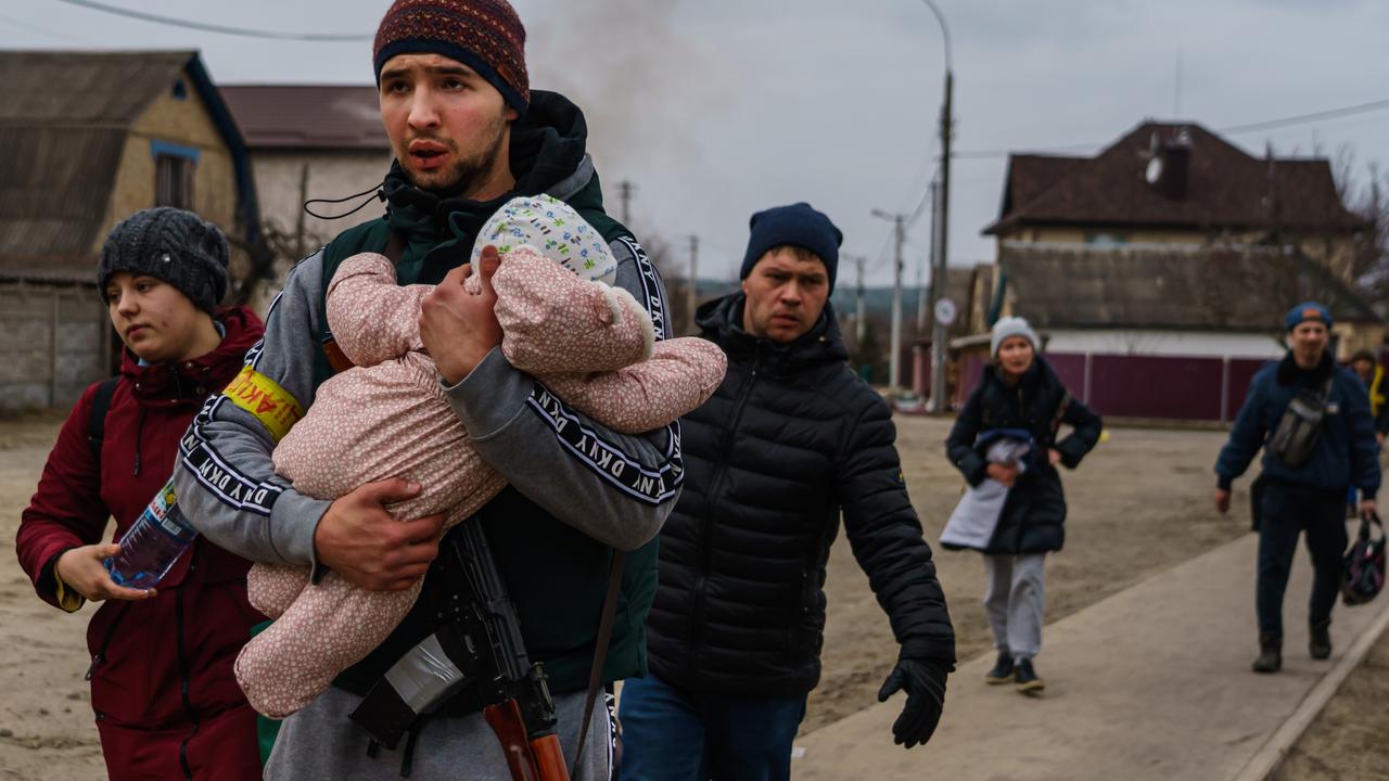A Ukrainian volunteer fighter helps carry a child for local residents as they evacuate on foot as Russian forces advance and continue to bombard the area with artillery, in Irpin, Ukraine, Sunday, March 6, 2022. Picture: Marcus Yam / Los Angeles Times