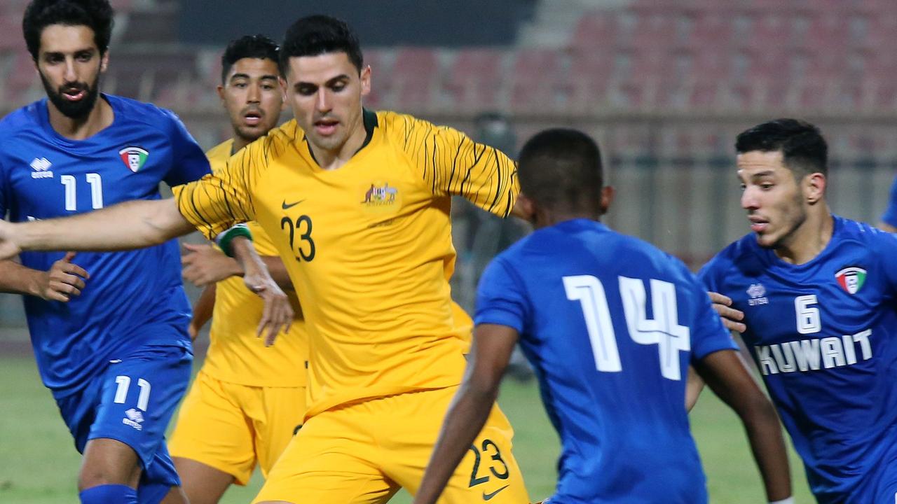 Australia's Tom Rogic kicks the ball past Kuwait's Dhari Saed (C) and Sultan al-Enizi