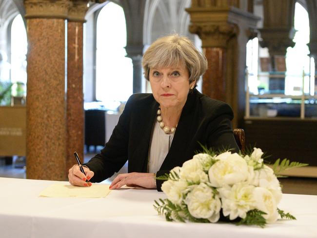 Britain's Prime Minister Theresa May writes a message in a book of condolence at Manchester Town Hall. Picture: AFP