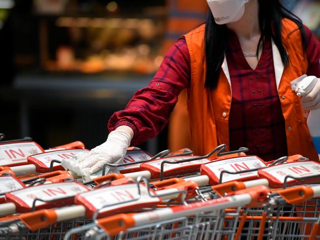 A supermarket employee desinfects shopping carts in Vienna, Austria. The Austrian Government will now require people to wear medical grade masks even outdoors. Picture: Thomas Kronsteiner/Getty Images