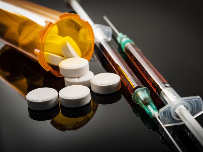 Opioid epidemic, drug abuse concept with closeup on two heroin syringes or other narcotics surrounded by scattered prescription opioids. Oxycodone is the generic name for a range of opioid painkillers