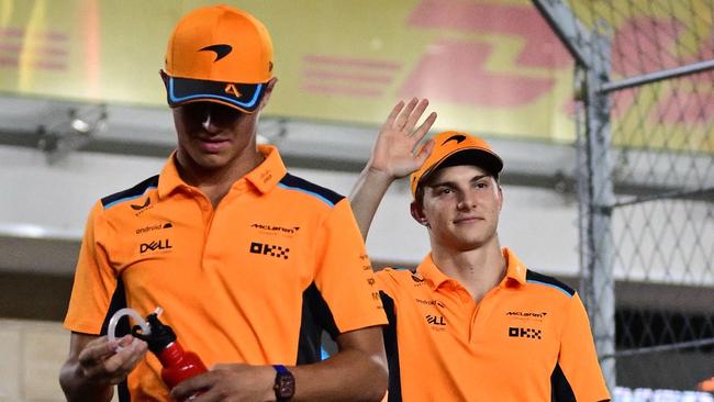 McLaren's British driver Lando Norris (L) and McLaren's Australian driver Oscar Piastri (R) wave to the fans ahead of the Qatari Formula One Grand Prix at Lusail International Circuit on October 8, 2023. (Photo by Ben Stansall / AFP)