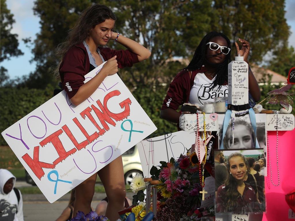 A 9th grader at Marjory Stoneman Douglas High School, holds a sign that reads, 'You are Killing Us,' as she visits the memorial set up in front of the school. Picture: AFP