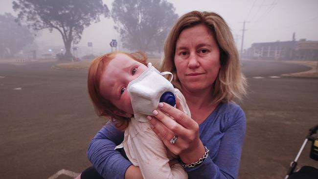 Mum Laura Langmead tries to put a breathing mask over her daughter Evie 1, to help filter the smoke blanketing Mallacoota. Picture: David Caird