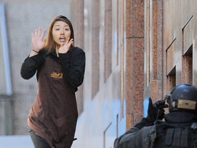 A hostage runs from the Lindt Chocolat cafe in Martin Place, Sydney, Monday, Dec. 15, 2014. Five hostages have fled from a cafe in central Sydney where an unknown number of people are being held hostage. (AAP Image/Joel Carrett) NO ARCHIVING