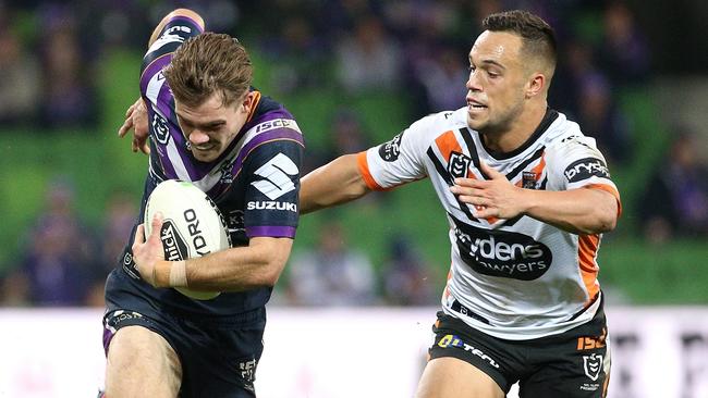 Ryan Papenhuyzen of the Storm (left) runs the ball forward under pressure from Luke Brooks of the Tigers during the Round 10 NRL match between the Melbourne Storm and the Wests Tigers at AAMI Park in Melbourne, Thursday, May 16, 2019. (AAP Image/Hamish Blair) NO ARCHIVING, EDITORIAL USE ONLY