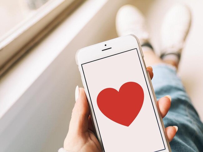 A smartphone with a red heart on the display held by a woman.