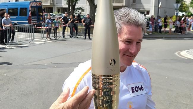 Sneesby smiles broadly as he carries the Olympic flame.