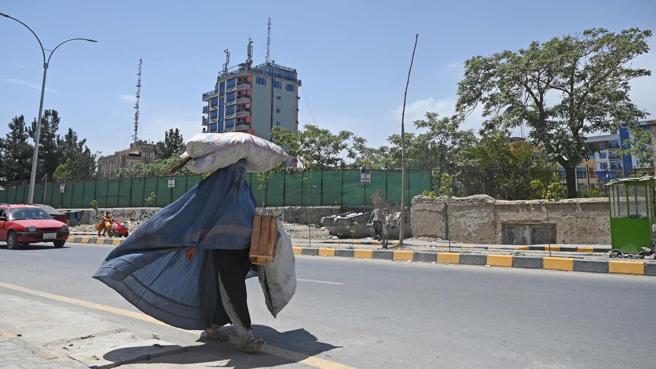 A burqa clad woman carrying a sack on her head walks along a road in Kabul on August 7, 2021. Picture: Sajjad Hussain/AFP