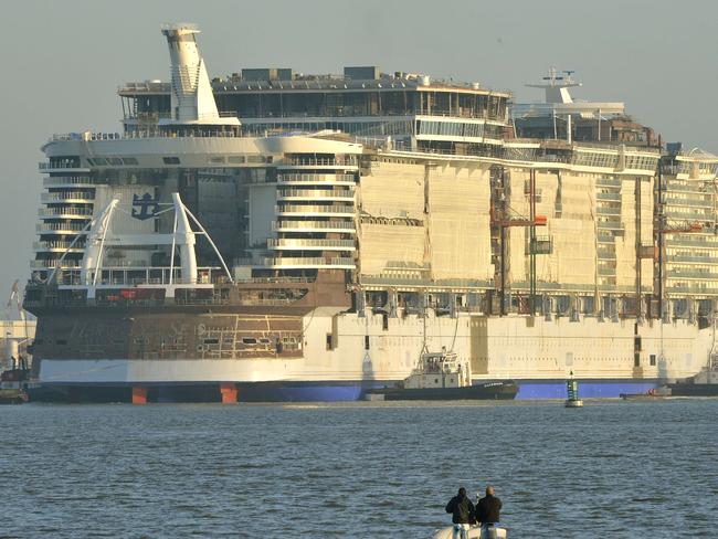 TOPSHOTS Fishing boats pass by as the cruise liner "Harmony of the Seas" is towed by tug boats into its new moorings at the STX Shipyards in Saint-Nazaire on June 19, 2015. The cruise liner, one of the largest ever built, with a capacity of 6,000 passengers is scheduled for delivery in April 2016. AFP PHOTO / GEORGES GOBET