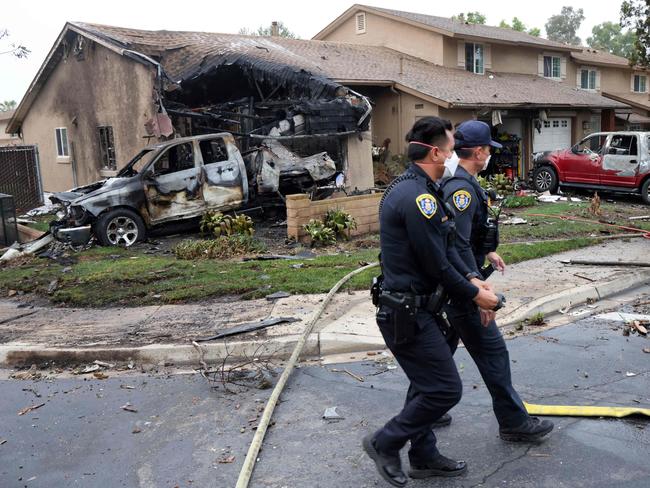 Police officers search the site where a small plane crashed on a California street. Picture: AFP