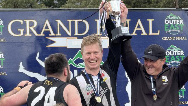 Belgrave captain Michael Sproules (middle) holds the cup aloft. On the left (No. 24) is club president Harley McDermott.