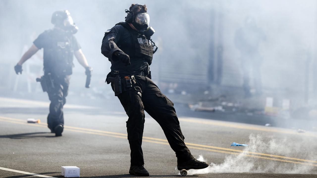 A police officer kicks a tear gas canister deployed to disperse a crowd in Philadelphia. Picture: AP