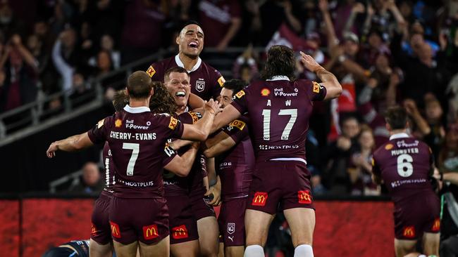 Queensland players mob Collins after his jump.