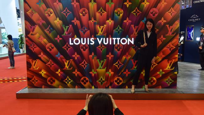 A woman poses for a picture next to a Louis Vuitton stand during the second China International Import Expo in Shanghai. Picture: AFP