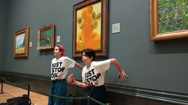 Just Stop Oil activists glued to the wall under Vincent van Gogh's Sunflowers after throwing tomato soup on the painting at the National Gallery in London. Picture: AFP