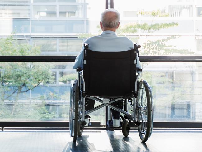 Senior Man in Wheelchair looking out of a window in a hospital corridor. Elder abuse. Picture: iStock