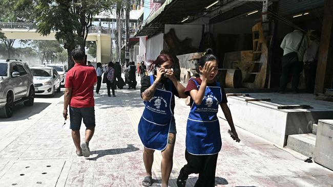 Women react in Bangkok on March 28, 2025, after an earthquake. A powerful earthquake rocked central Myanmar on March 28, buckling roads in capital Naypyidaw, damaging buildings and forcing people to flee into the streets in neighbouring Thailand. (Photo by Lillian SUWANRUMPHA / AFP)