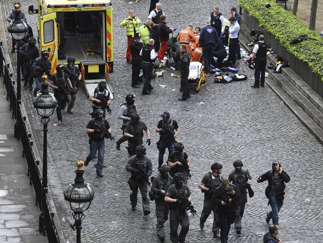 Armed police walk past emergency services attending to injured people outside the Houses of Parliament in London. Picture: Stefan Rousseau/PA via AP