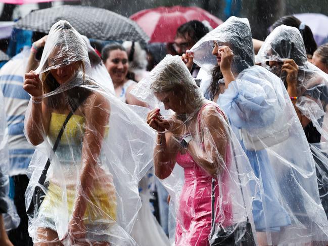 Fans of US singer Taylor Swift, also known as a Swifties, shelter from the rain as they arrive for Swift's concert in Sydney on Friday. Picture: DAVID GRAY / AFP