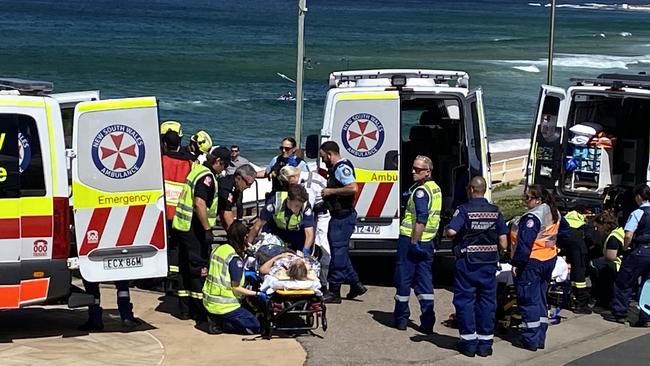 A woman is loaded into an ambulance, injured after a car plunged off a cliff at Bar Beach, Newcastle. Picture Amy Ziniak