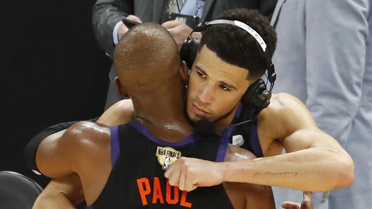 PHOENIX, ARIZONA - JULY 06: Devin Booker #1 and Chris Paul #3 of the Phoenix Suns hug after the team's win against the Milwaukee Bucks following Game One of the NBA Finals at Phoenix Suns Arena on July 06, 2021 in Phoenix, Arizona. NOTE TO USER: User expressly acknowledges and agrees that, by downloading and or using this photograph, User is consenting to the terms and conditions of the Getty Images License Agreement. (Photo by Chris Coduto/Getty Images)