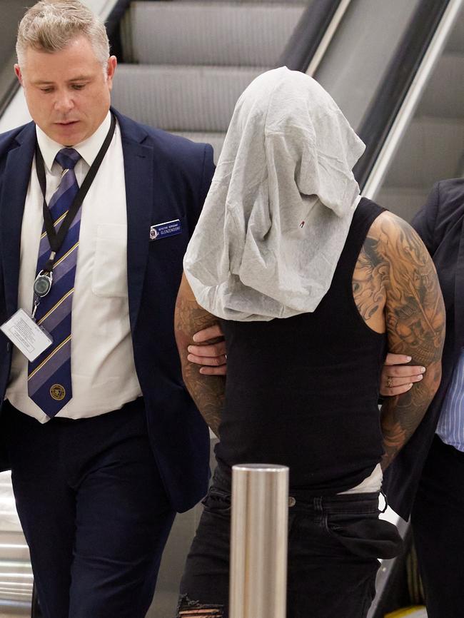 Pham is led through Sydney International Airport by detectives on Sunday after being arrested before he could board a plane to Vietnam. Picture: NSW Police