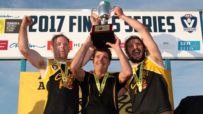 YCW coach Wayne Capp and co captains Jie Coghlan and Ken Lylak hold up the Premiership Cup during the Peninsula League Grand Final between Frankston YCW and Bonbeach played at Kars Park in Frankston on Sunday 17th September, 2017. Picture: Mark Dadswell