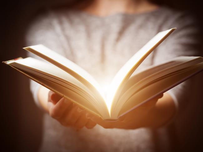 Light coming from book in woman's hands in gesture of giving, offering. Concept of wisdom, religion, reading, imagination.