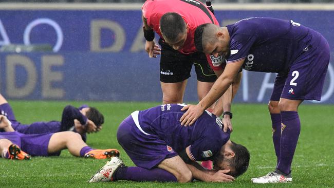Fiorentina's midfielder and new captain Milan Badelj (bottom) reacts as referee Fabrizio Pasqua and Fiorentina's defender Vincent Laurini (R) comfort him, on March 11, 2018 at the end of the Italian Serie A football match Fiorentina vs Benevento