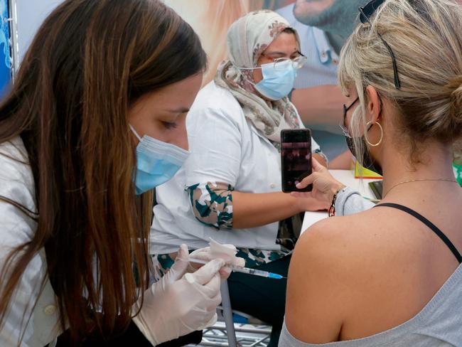 A Israeli healthcare worker vaccinates a woman against the COVID-19 coronavirus at Clalit Health Services, in the coastal city of Tel Aviv, on January 3, 2021. - Israel said two million people will have received a two-dose COVID-19 vaccination by the end of January, since the start on December 19, of an aggressive push to administer the vaccine made by US-German pharma alliance Pfizer-BioNTech. (Photo by JACK GUEZ / AFP)