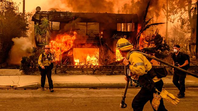 TOPSHOT - Firefighters work the scene as an apartment building burns during the Eaton fire in the Altadena area of Los Angeles county, California on January 8, 2025. At least five people are now known to have died in wildfires raging around Los Angeles, with more deaths feared, law enforcement said January 8, as terrifying blazes leveled whole streets, torching cars and houses in minutes. More than 1,000 buildings have burned in multiple wildfires that have erupted around America's second biggest city, forcing tens of thousands of people from their homes. (Photo by JOSH EDELSON / AFP)