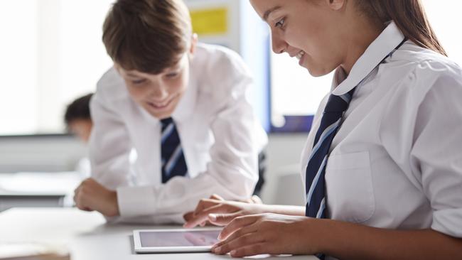 Two High School Students Wearing Uniform Working Together At Desk Using Digital Tablet Picture: Istock