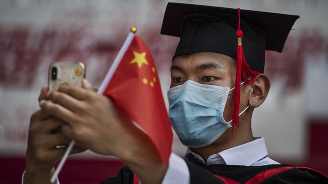 A Chinese student from Renmin University of China holds a flag as he takes a selfie after his graduation ceremony at the school's campus in Beijing, China.