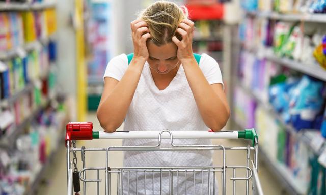 Upset woman in a supermarket with an empty shopping trolley. Crises, rising prices for goods and products. Woman shopping at the supermarket.