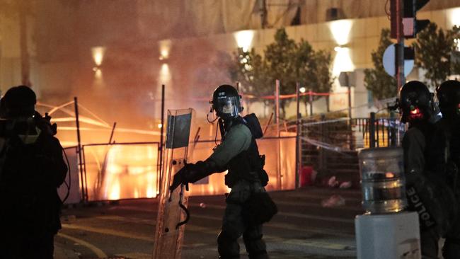 Police officers take their position as barricades lit by protesters burn. Picture: AP