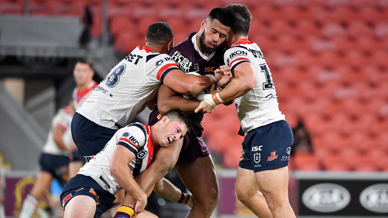 Payne Haas is collared by three Roosters players.