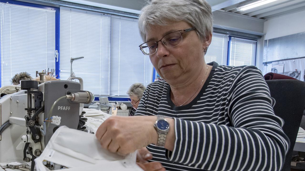 An employee of the textile company Br'ndl in Geyer, Germany sews face masks Tuesday, March 24, 2020. The masks are made of an antibacterial fabric in which threads of pure silver are woven. With this innovative technical textile, the company from the Erzgebirge Mountains has been fighting against hospital germs for a long time. What was previously too expensive for many hospitals is becoming interesting in the new coronavirus crisis. The company is now switching to face masks and protective clothing. For most people, the new coronavirus causes mild or moderate symptoms, such as fever and cough that clear up in two to three weeks. For some, especially older adults and people with existing health problems, it can cause more severe illness, including pneumonia and death. (Hendrik Schmidt/dpa-Zentralbild via AP)