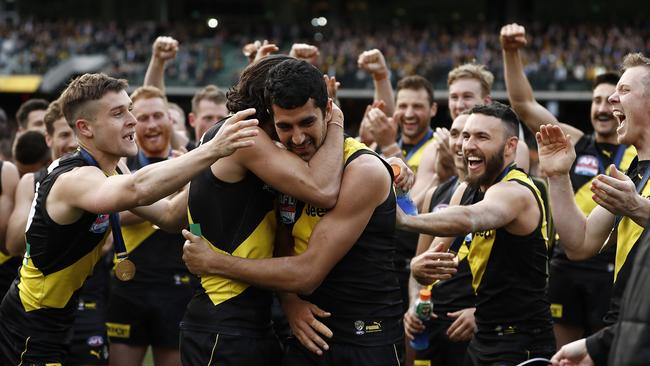 Marlion Pickett is embraced by his teammates as he prepares to receive his premiership medal.