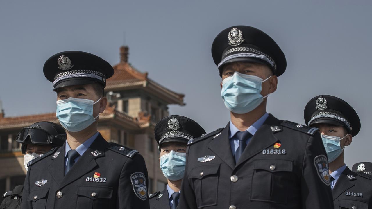 Chinese police officers wear protective masks as wait to observe three minutes of silence to mark the country's national day of mourning for COVID-19 in Beijing . Picture: Kevin Frayer/Getty Images.